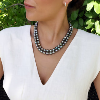 Two layered handmade pearl strands Hawaii worn by a model against a leafy backdrop.