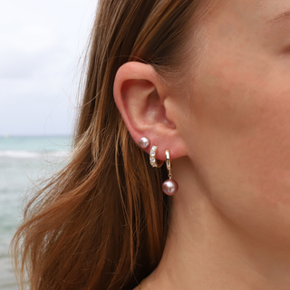 Handcrafted earrings honolulu worn by a model at the beach, featuring pearls and gold accents.