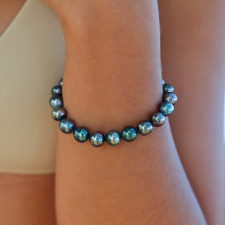 Woman wearing Tahitian knotted pearl bracelet stacked with gold bangles, Misha Hawaii
