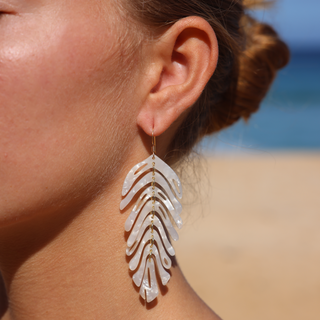 Woman wearing banana leaf statement drop earrings, Misha Hawaii