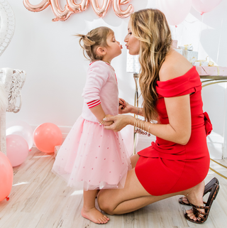 mom and daughter kissing wearing matching pink pearl bracelets