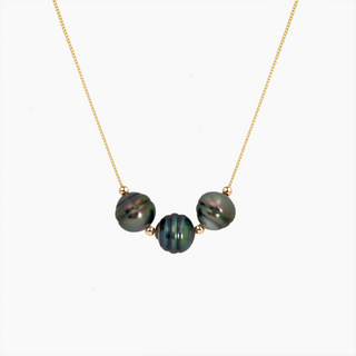 A delicate gold chain necklace featuring three round, iridescent peacock pearls with gold spacers, displayed against a clean white background.