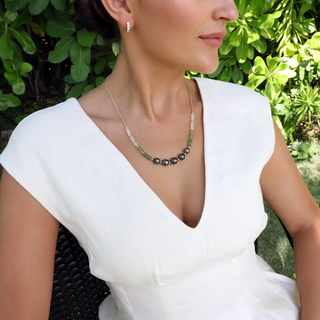 Tahitian black pearl necklace with green gemstones and gold chain on model