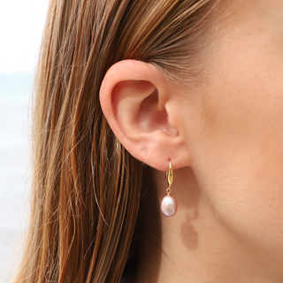 Beautiful woman wearing pink pearl french earrings with gold vermeil, showcasing elegance and style.