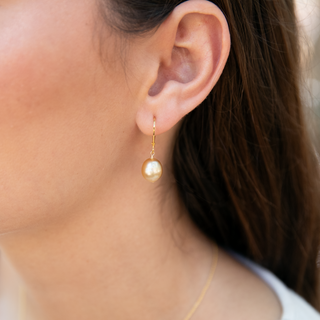 Close-up of a model wearing golden south sea pearl earrings.