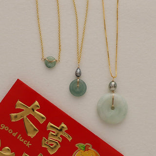 Large jade tahitian keshi pearl necklace displayed with green jade pendants on gold chains and a lucky red envelope.