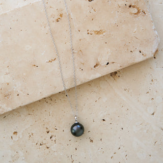 tahitian black pearl necklace gold on a tile flat lay