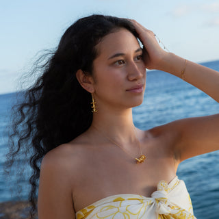 Model wearing Puakenikeni flower earrings in gold handcrafted in Hawaii