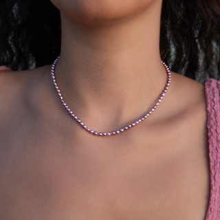 Model wearing a delicate pink keshi pearl strand necklace, showcasing its beautiful luster and unique organic shape.