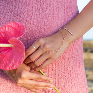 Pink pearl hand chain with ring and bracelet on hand with flower