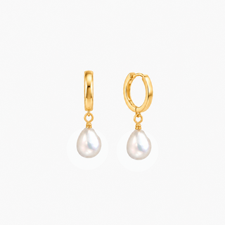 A pair of gold huggie hoop earrings with dangling pink freshwater pearls, shown against a plain light gray background.
