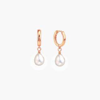 A pair of rose gold huggie hoop earrings with teardrop-shaped white freshwater pearls hanging from the hoops, shown against a plain light gray background.