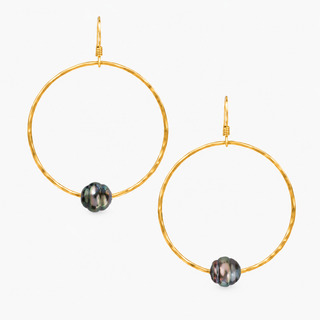 A pair of gold hoop earrings with a small iridescent dark gray bead hanging from the bottom of each hoop, shown against a plain white background.