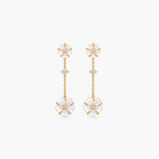 A pair of gold dangle earrings with white mother-of-pearl flower charms and small clear crystal accents, shown against a plain white background.
