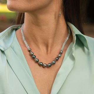 Model wearing an aquamarine and tahitian pearl necklace with a silver grey hue, displayed against a light green shirt.